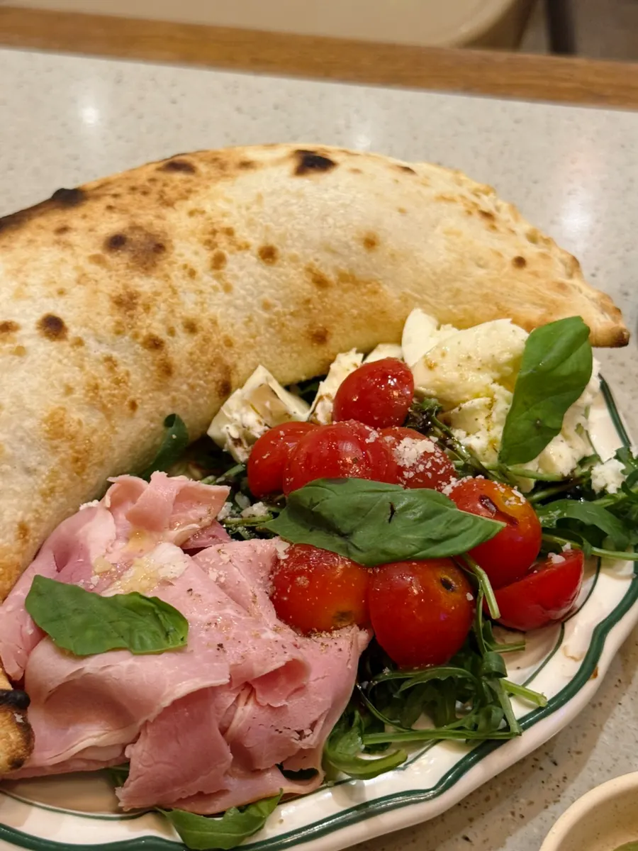 Tomato caprese served alongside the calzone