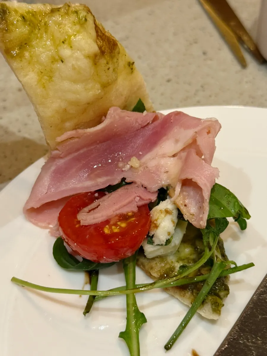 A bite of calzone topped with jambon and arugula