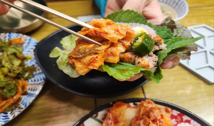 A wrap of skate, bossam and kimchi ready to eat