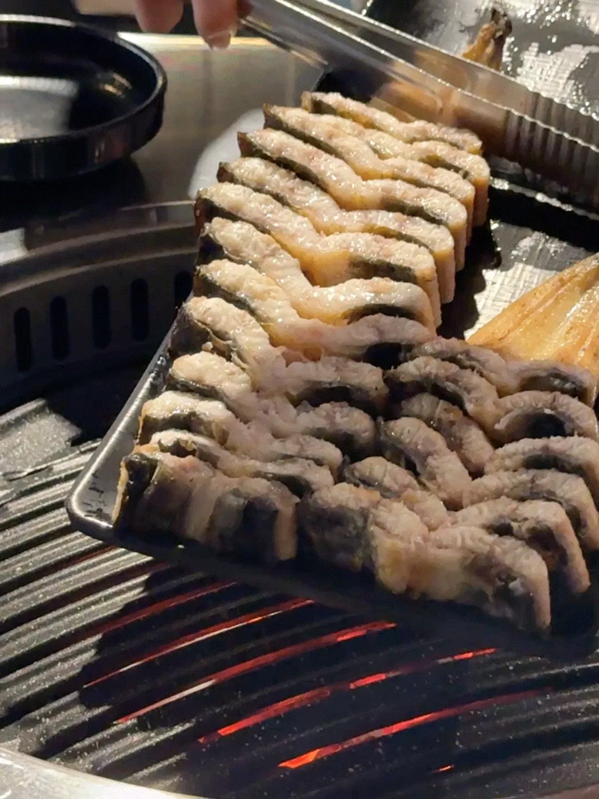 Bite-size grilled eel pieces placed on the charcoal grill