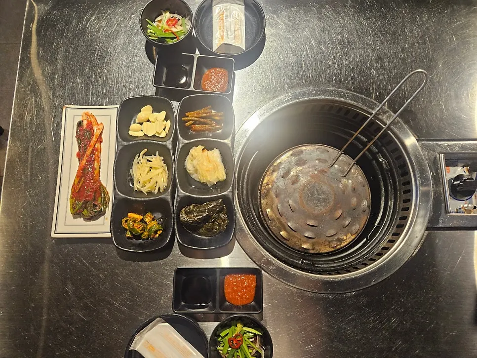 A spread of side dishes including green onion kimchi, ginger, and perilla leaf pickles