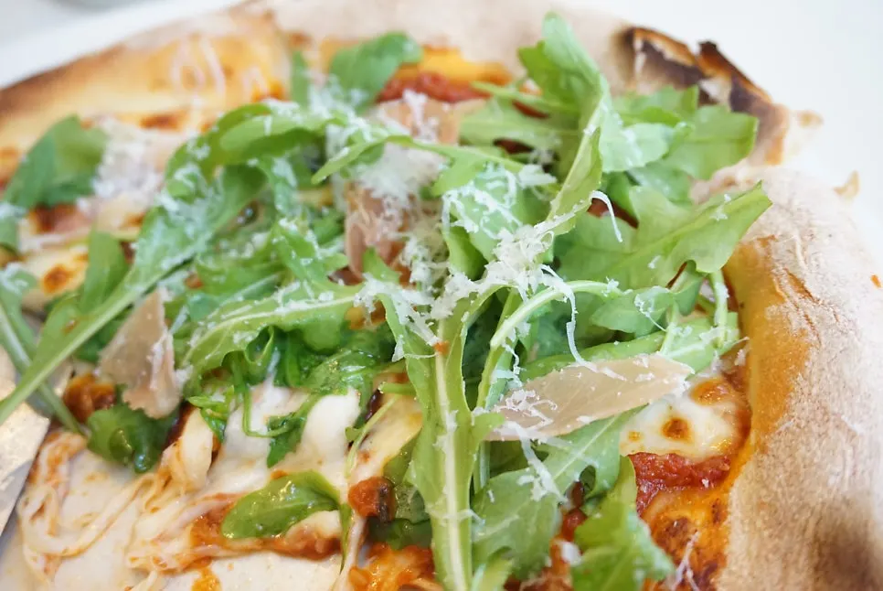 Pizza piled generously with arugula