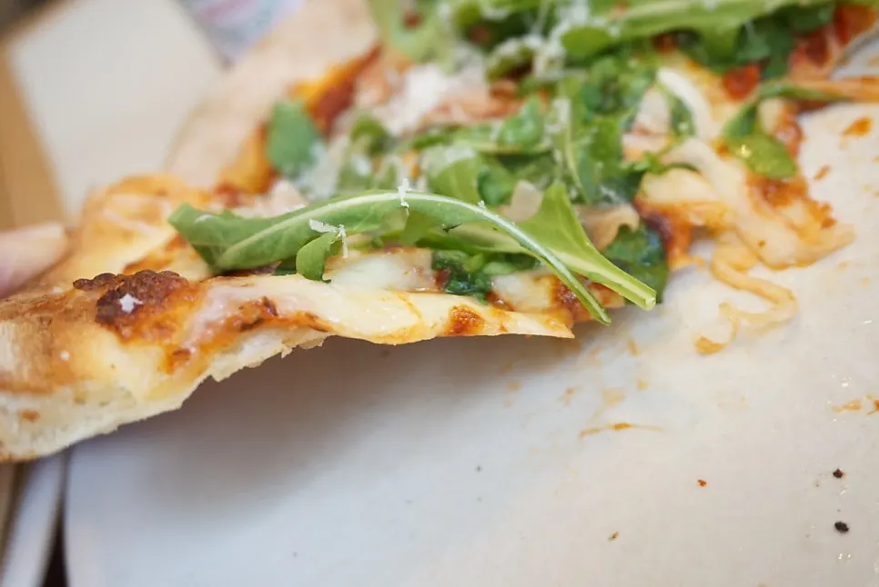 Thin, chewy crust of the arugula pizza