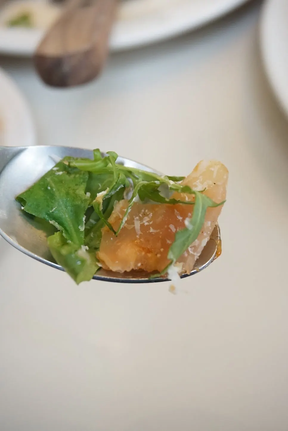 A slice of arugula pizza topped with prosciutto