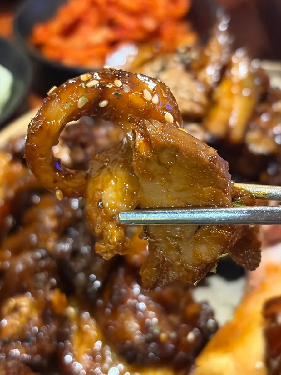 직화매운족발 한 점을 집어 든 모습