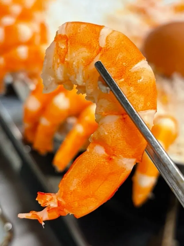 Plump king shrimp being peeled with gloves