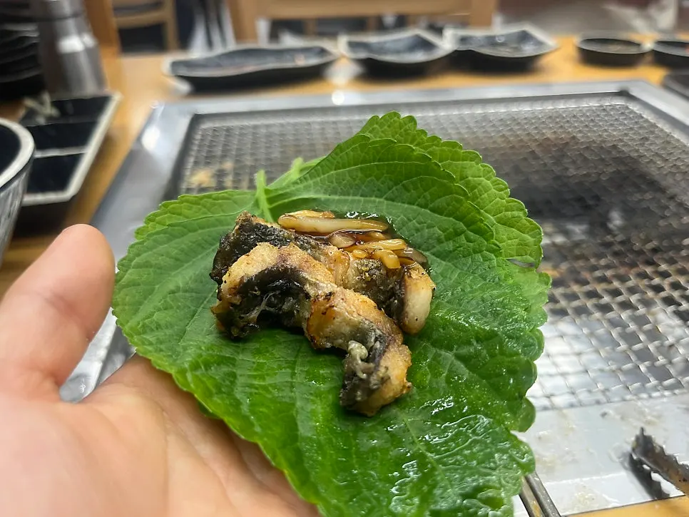 A piece of grilled eel topped with julienned ginger
