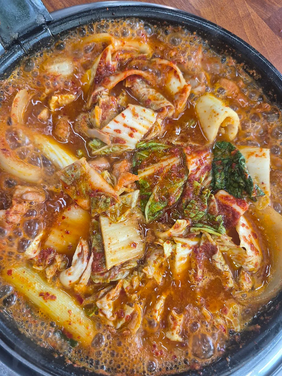 Gopchang hot pot boiling vigorously with cut kimchi mixed in