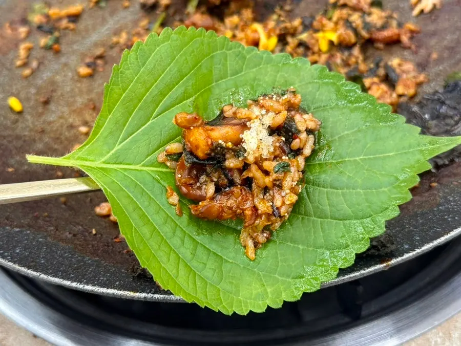 Satu sendok nasi goreng dengan telur ikan terbang yang pecah di mulut