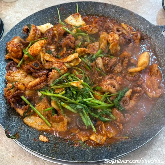 Hot-plate jjukkumi with extra sides and black pork belly, topped with minari