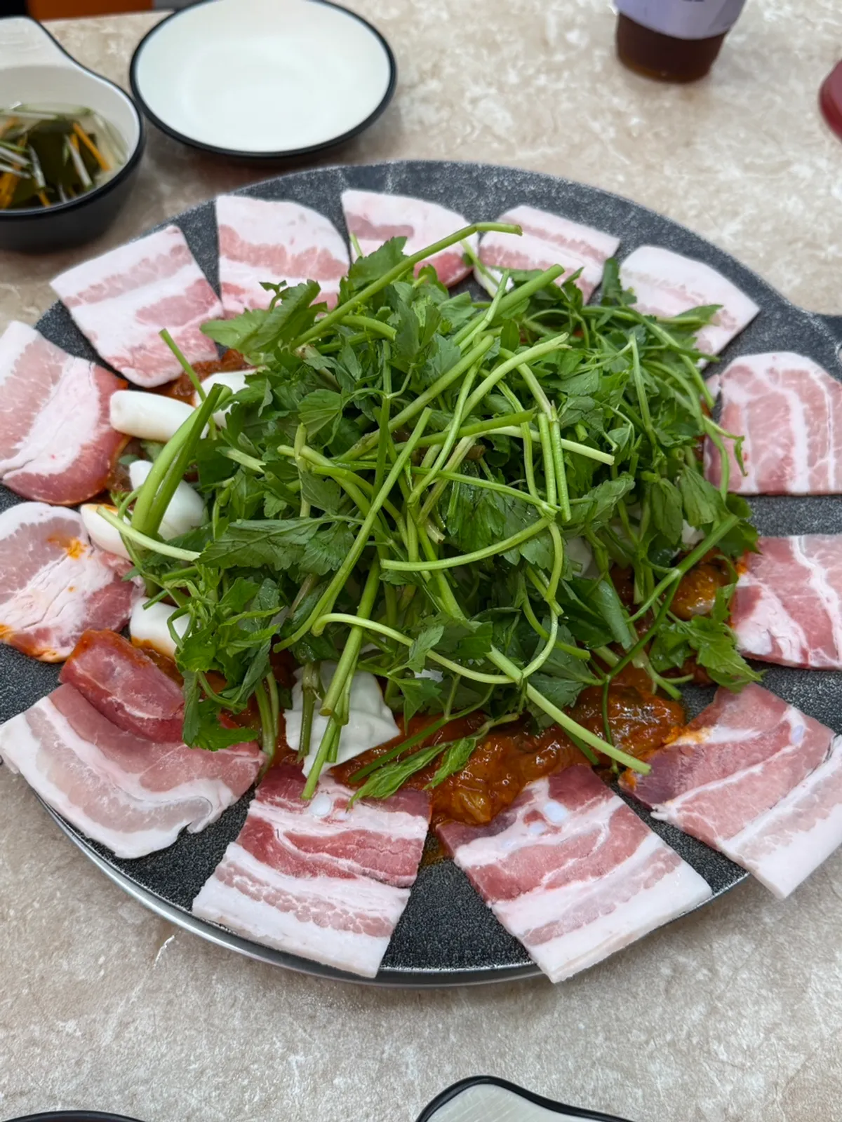 Hotplate jjukkumi with minari and pork belly before cooking