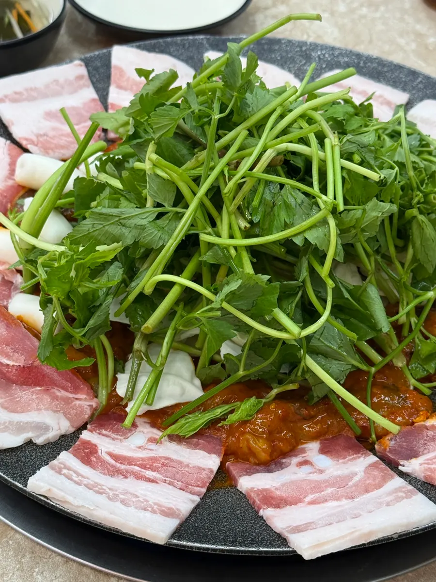 Close-up of hotplate piled with seasoned jjukkumi and vegetables