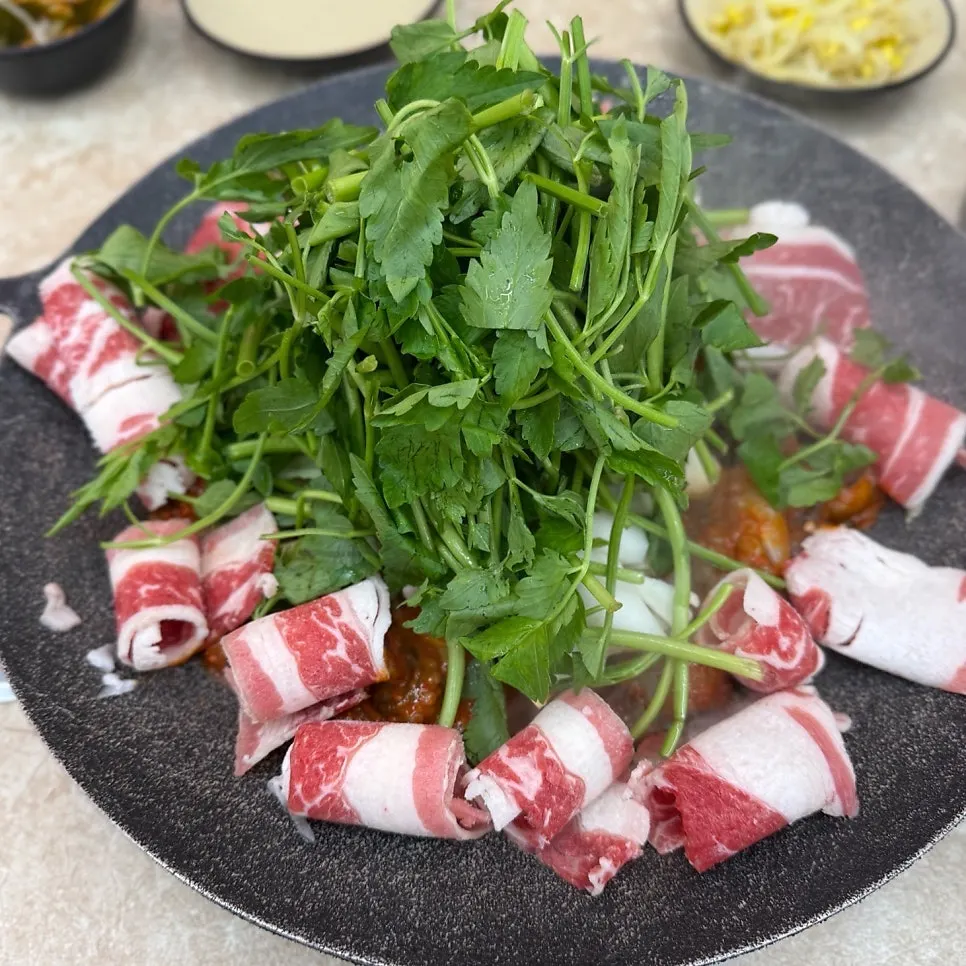 Hot-plate jjukkumi topped with minari and black angus beef belly