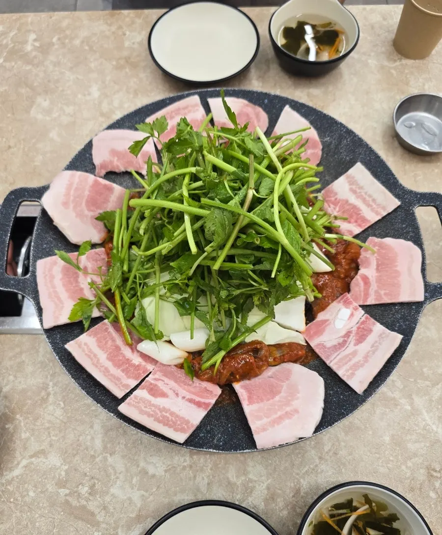 Griddle-cooked jjukkumi piled high with minari