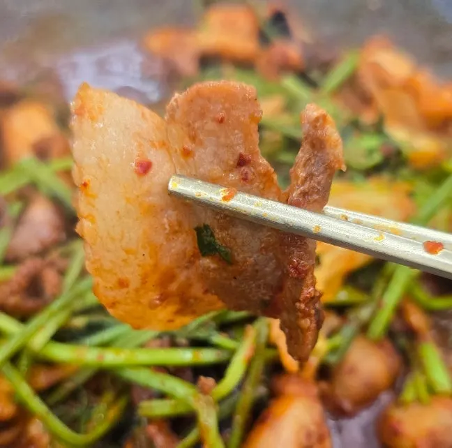 A bite combining jjukkumi and black pork belly