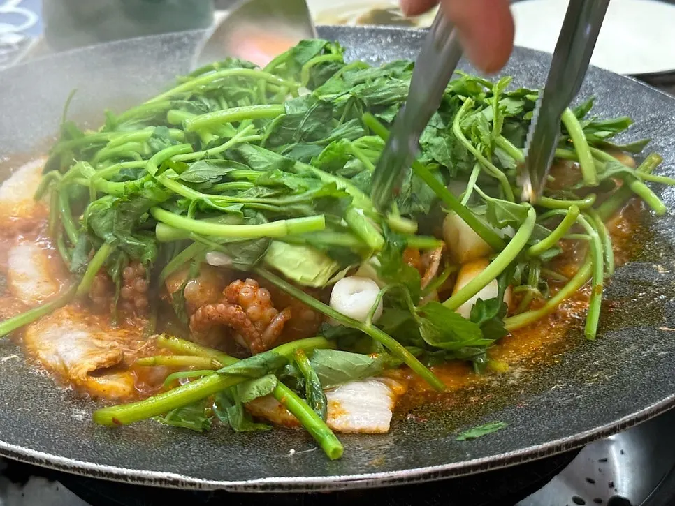 Jjukkumi and minari bubbling on the griddle