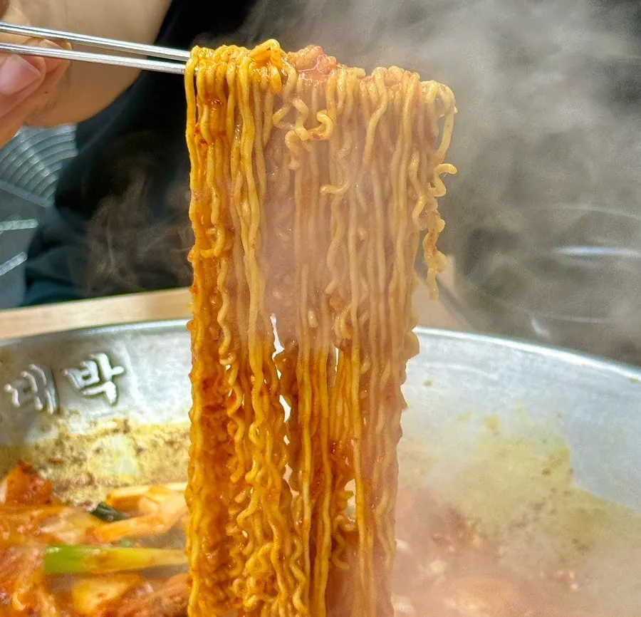 Sauce-soaked ramyeon noodles lifted out of the pot