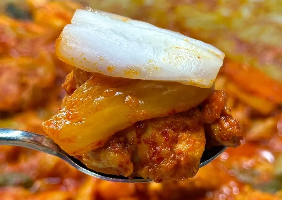 A bite of chicken meat topped with a side dish