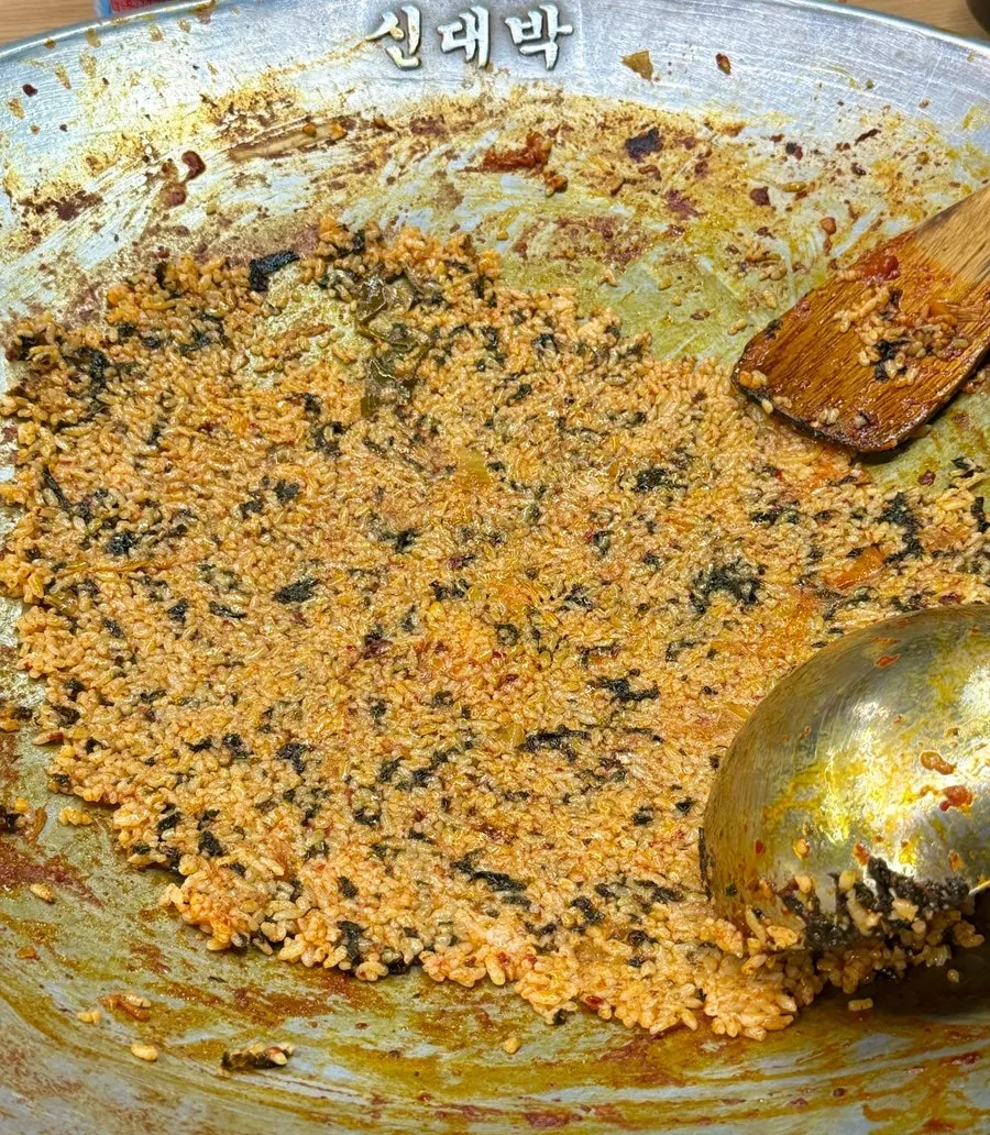 Finishing fried rice spread thin in the cast-iron pot