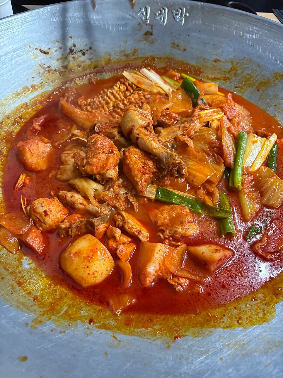Bubbling chicken stew topped with aged kimchi and green onion