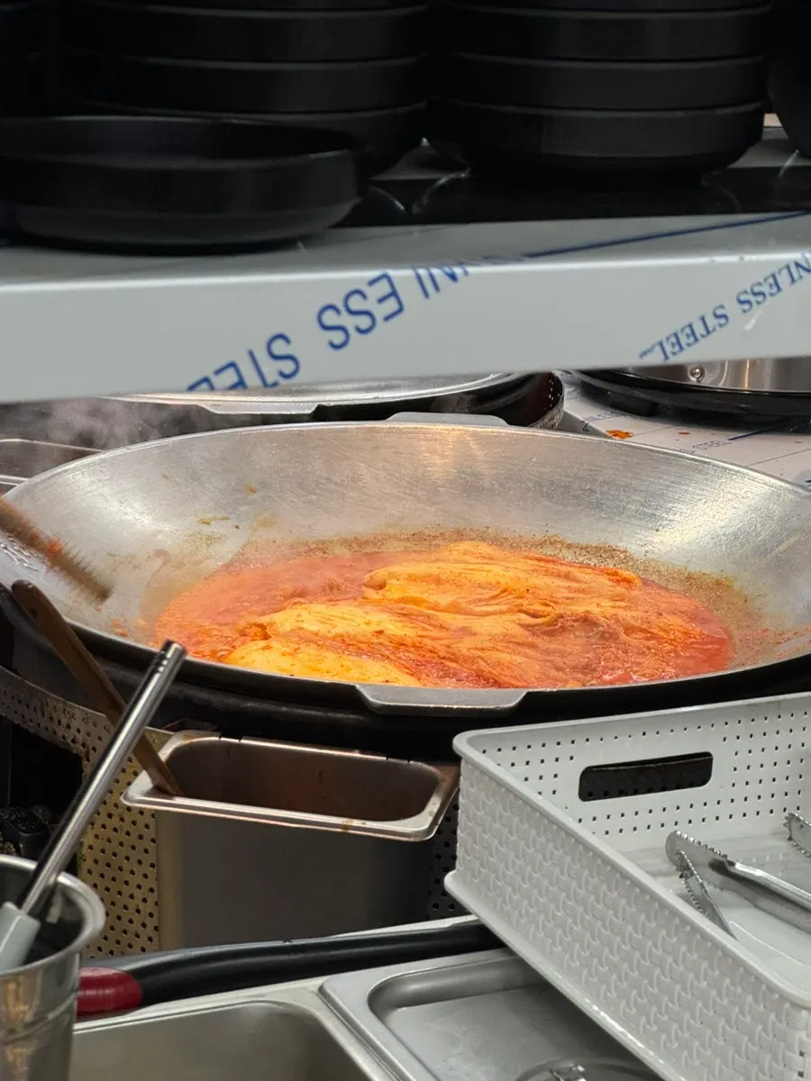 Owner cooking in a cast-iron pot next to the side dish refill station