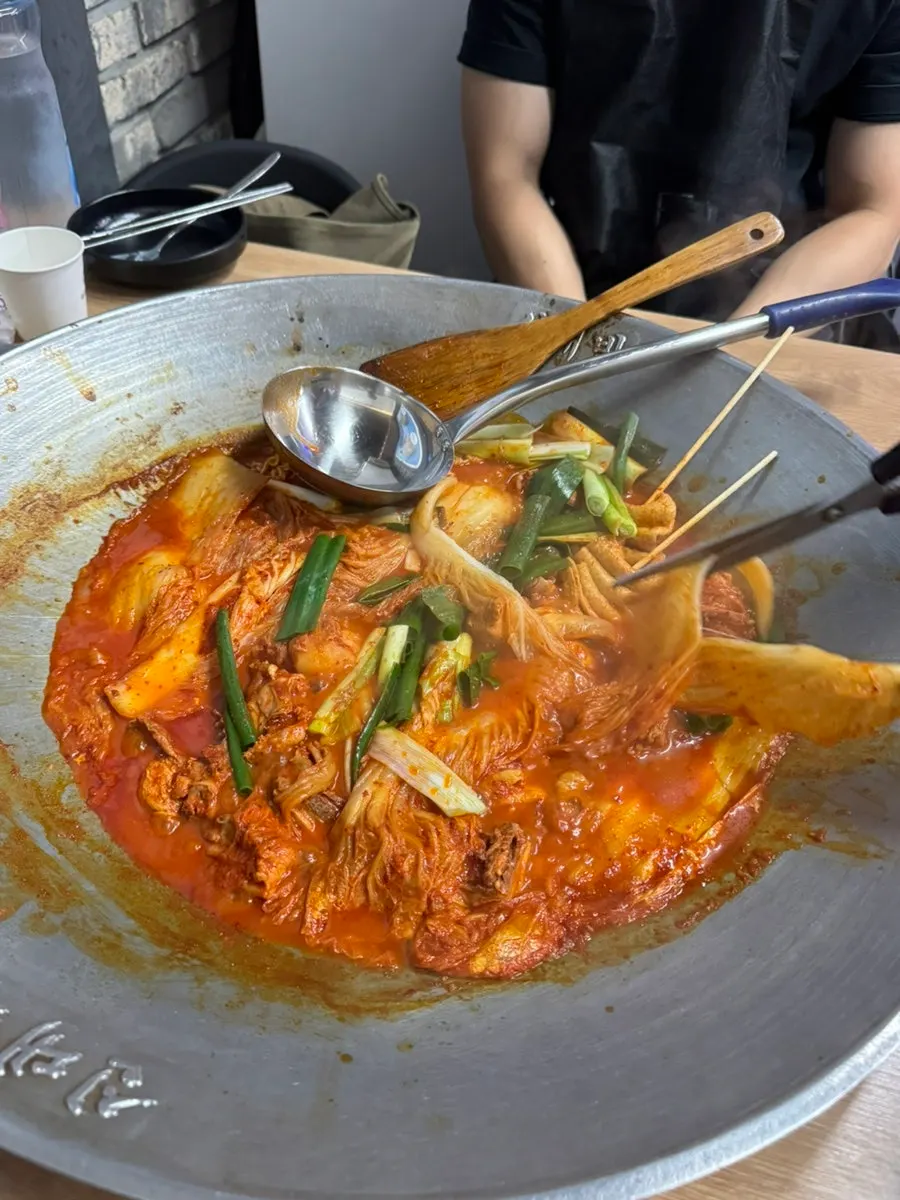 A large cast-iron pot of chicken stew placed on the table