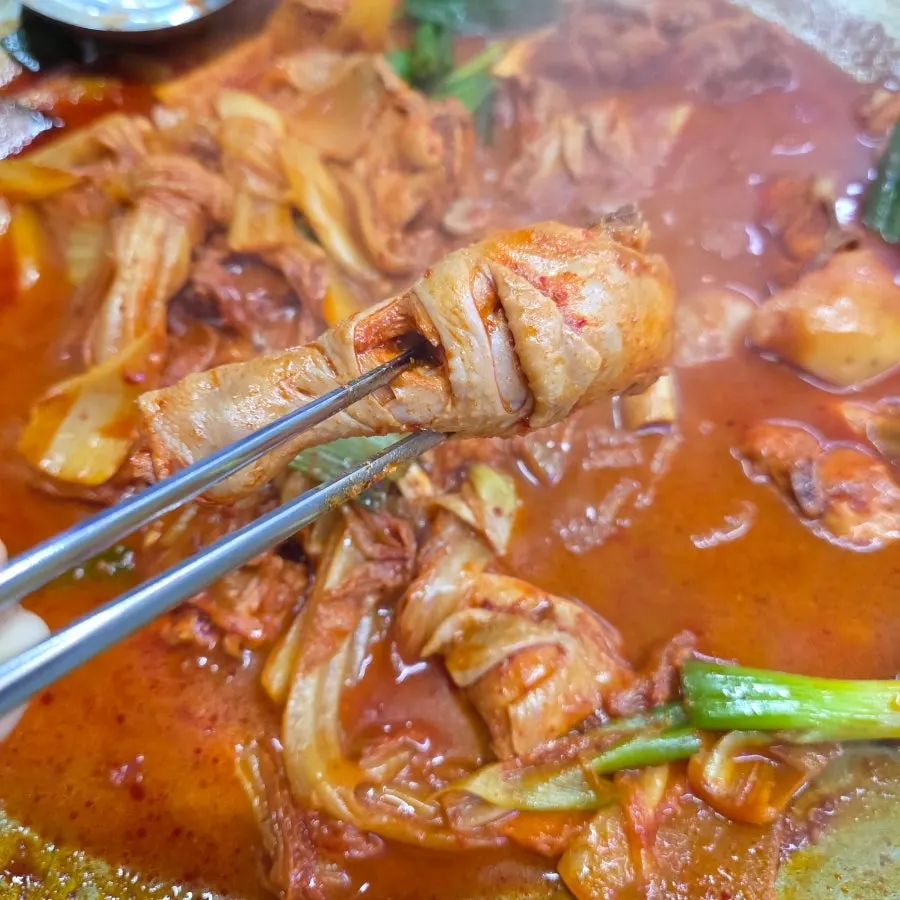 A piece of chicken leg picked up with chopsticks