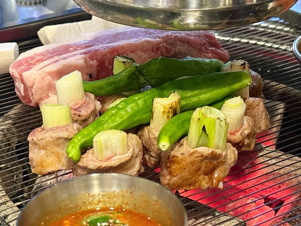 Staff grilling meat over charcoal
