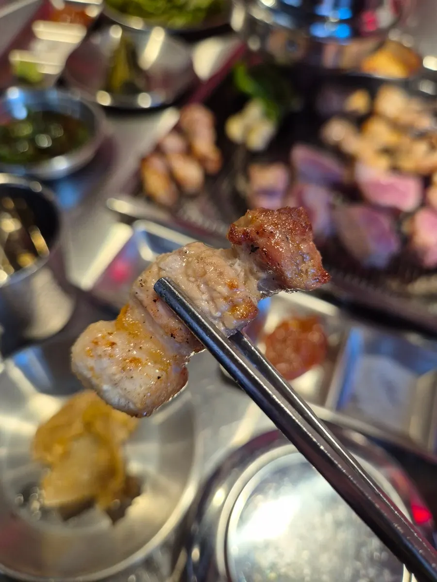 A piece of pork belly held with tongs