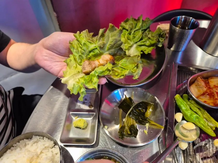 A wrap of meat with pickled scallions and lettuce