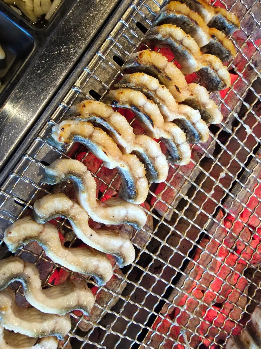 A staff member helping grill the eel on charcoal