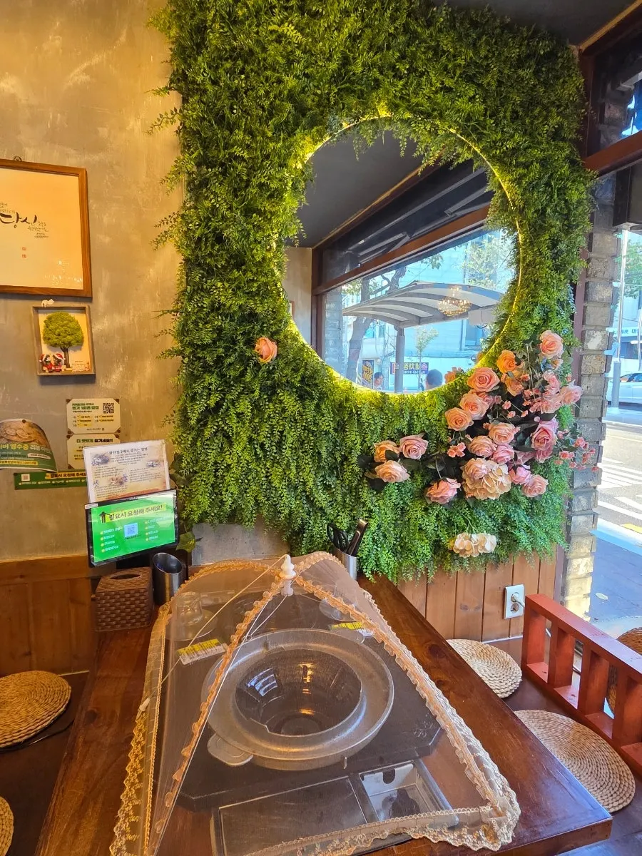 Wall with a round mirror surrounded by plants and roses
