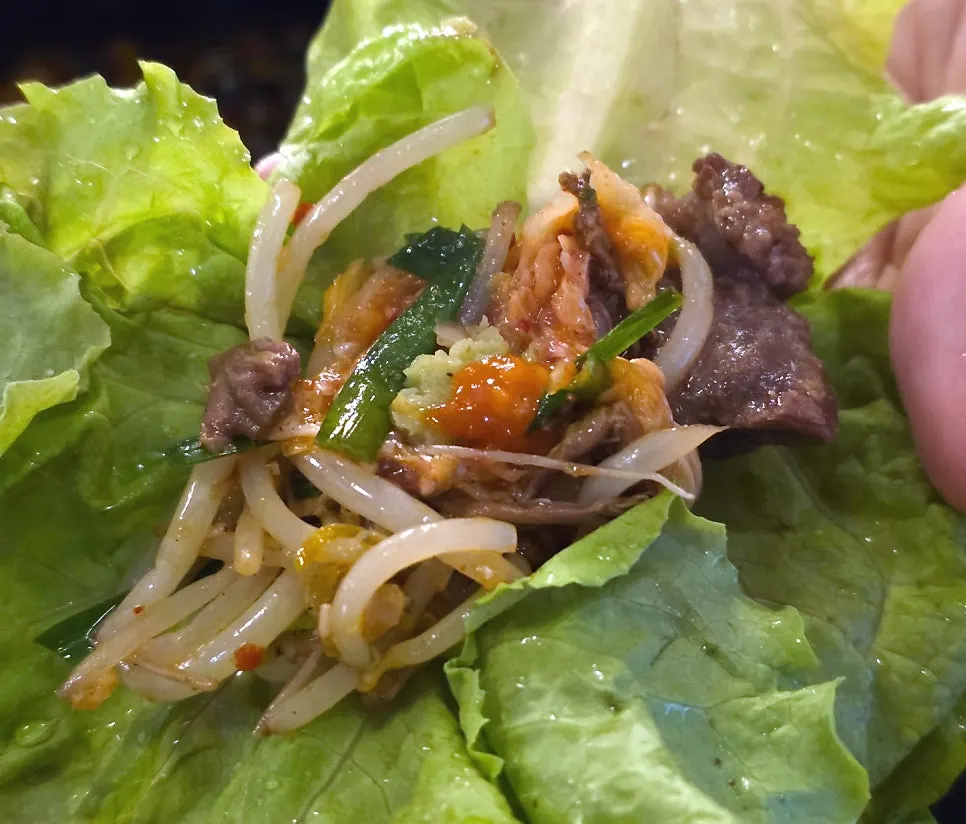 Braised green onion kimchi served with the mixed platter, alongside a piece of meat