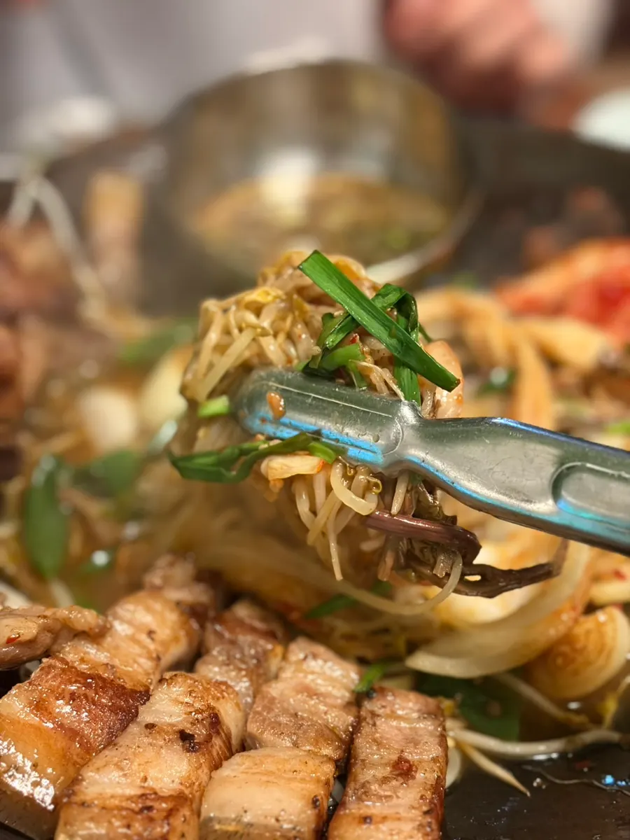 A piece of rare pork cut held with chopsticks