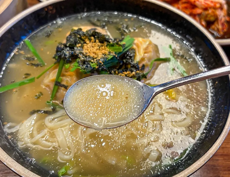 Kalmandu-guk topped with three kimchi dumplings