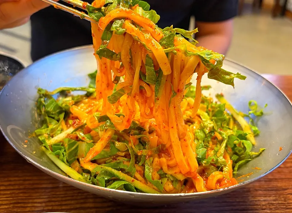 Bibim kalguksu topped with kimchi and minced meat