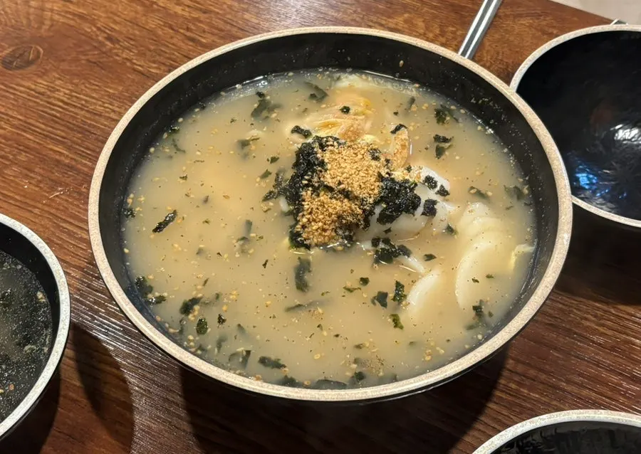 A bowl of rich warm broth with sesame seeds