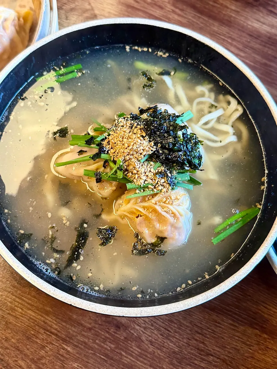 A bowl of dumpling kalguksu soup with kimchi dumplings