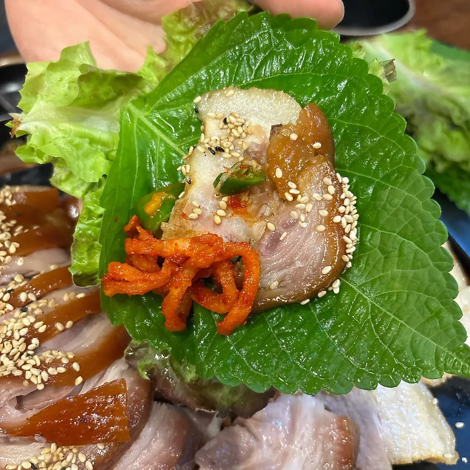 A wrap of jokbal and bossam topped with kimchi filling