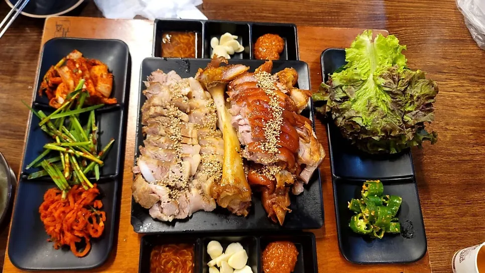 Full table with jokbal, bossam, and makguksu served together