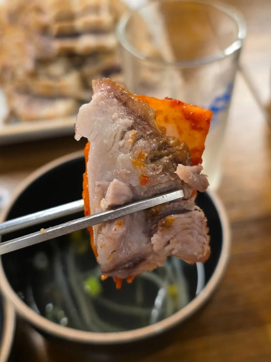 A piece of bossam eaten with dried radish strips