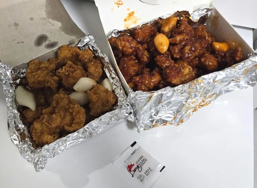 Two boxes of takeout — fried and seasoned dakgangjeong — set together