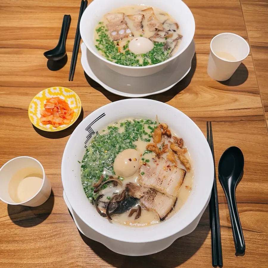 Table spread of gyedan ramen, motsu ramen, and tamagobap
