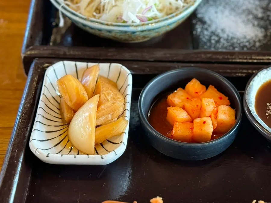 Side dishes of pickled onions and cubed radish kimchi
