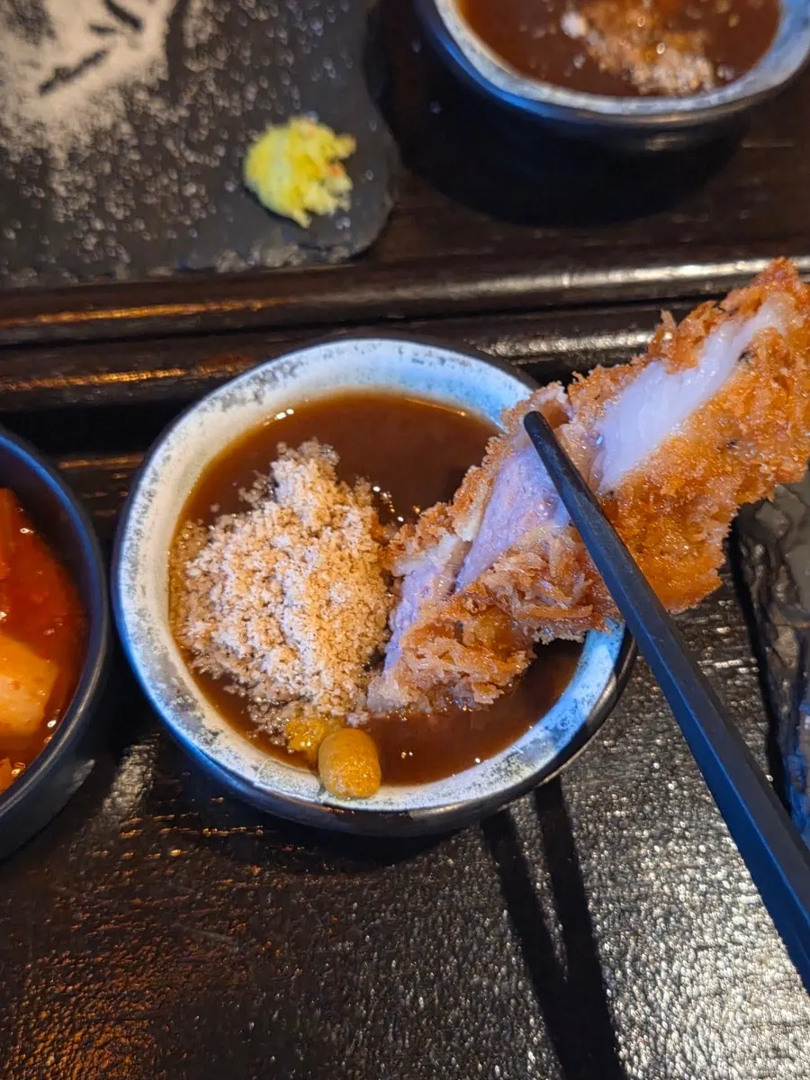 ピンクソルトを付けて食べる特上ロースかつの一切れ