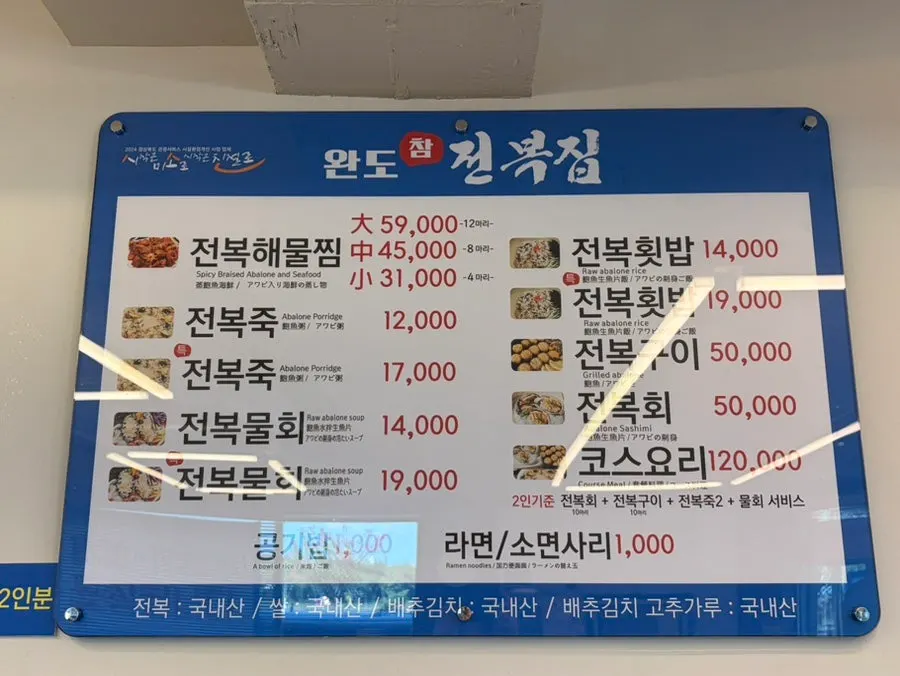 Menu board showing abalone seafood stew and abalone porridge at Wando Cham Jeonbokjip
