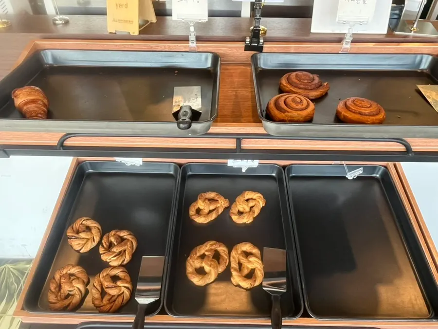Bakery display case with croissants and cinnamon rolls