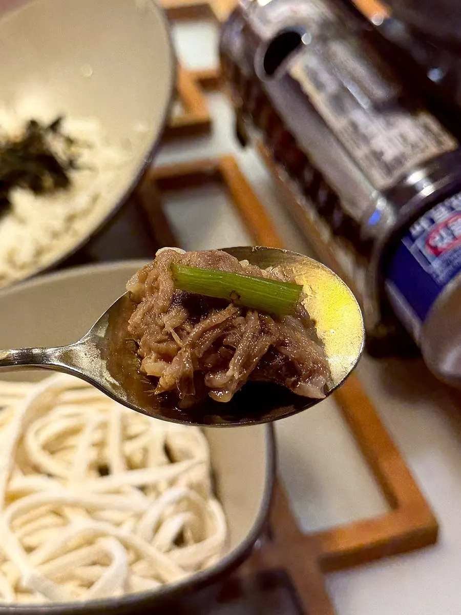 A bite of beef bone rib meat with minari and cabbage kimchi