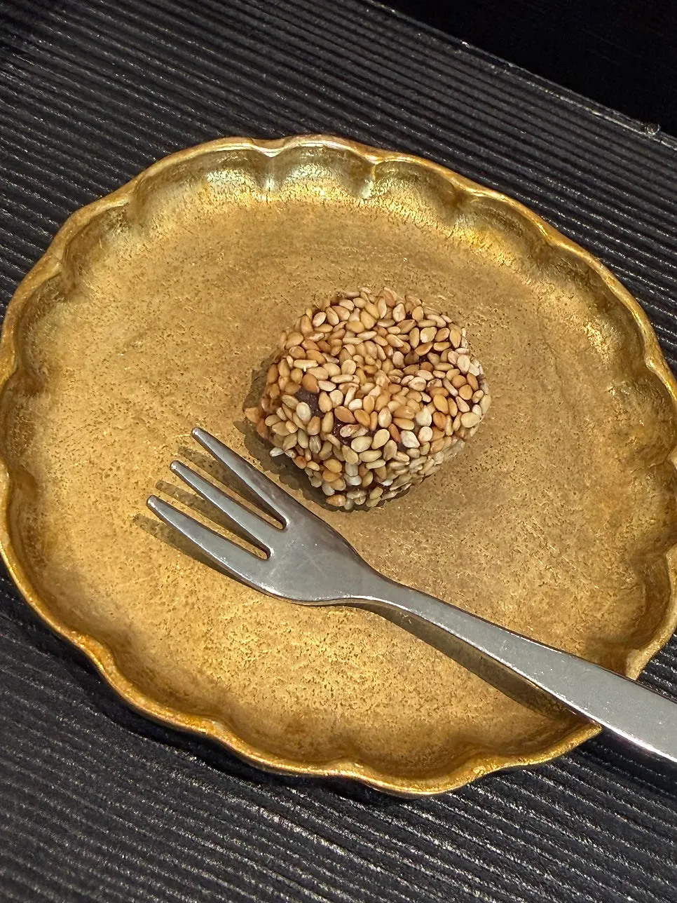 Bite-sized sesame-coated snack on a golden wave-patterned plate