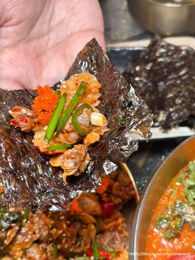 A spoonful of kkomak bibimbap topped with seaweed and flying fish roe